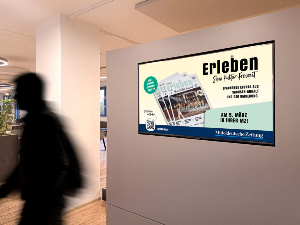 Digital‑Signage‑Motiv der Erleben Veranstaltungsbeilage 2026 auf Wandbildschirm in Innenraum