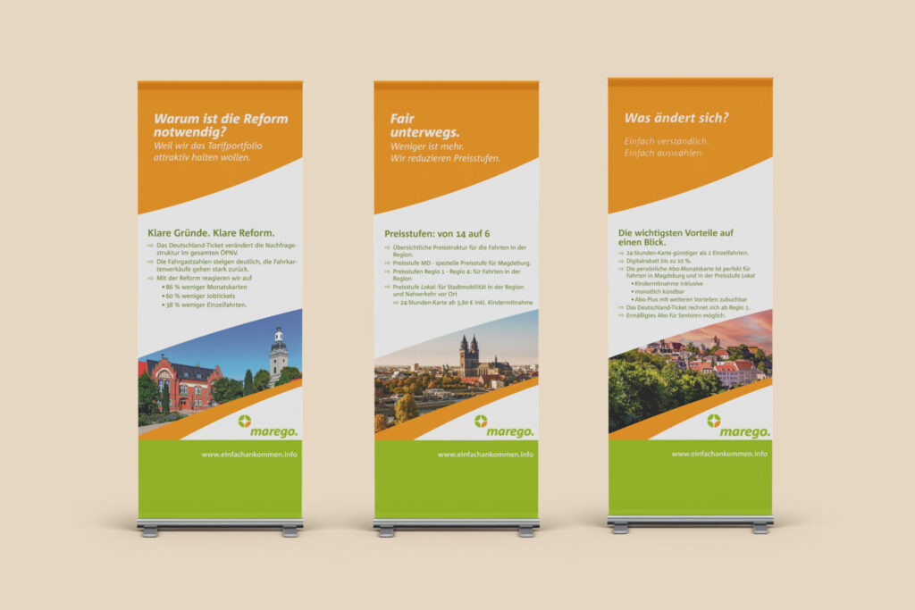 Three freestanding vertical banners with orange diagonal tops and green bottoms, displaying German informational text about reform, pricing, and changes, with town photos at the bottom.